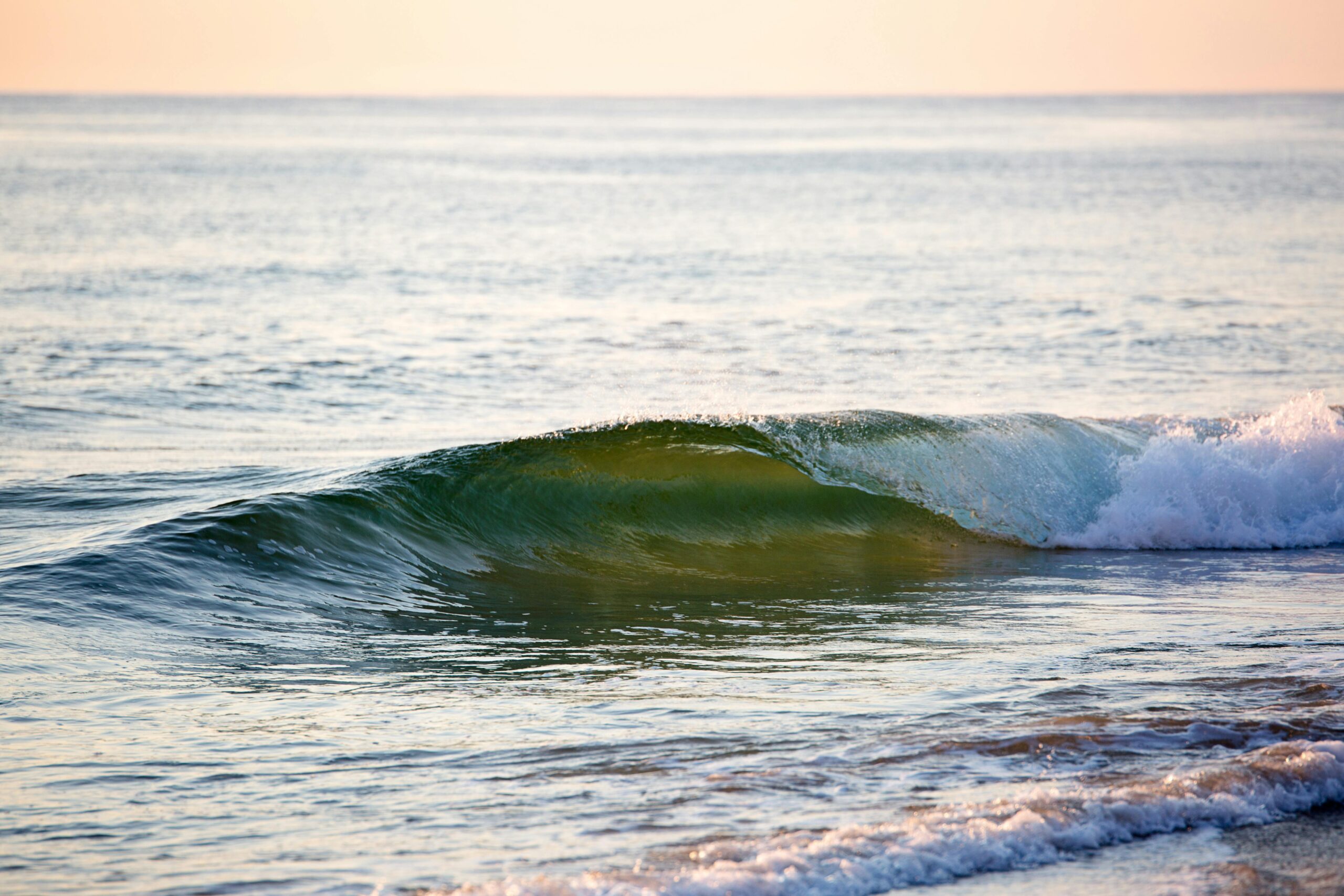 A gentle ocean wave captured at sunrise, showcasing the calmness of the sea and natural beauty.